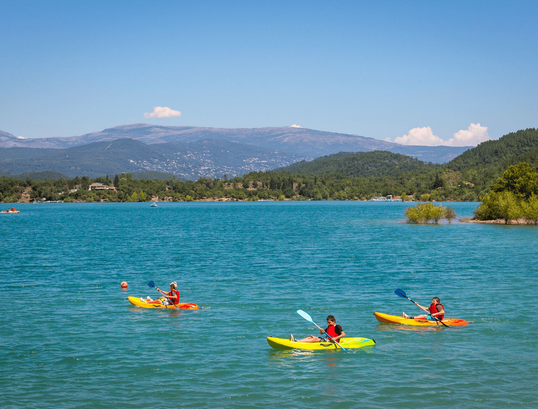Passer une journée au lac de Saint-Cassien, c’est s’offrir une vraie bouffée d’air frais entre nature, détente et activités ludiques. Ce grand lac artificiel, niché dans les collines entre le Var et les Alpes-Maritimes, est l’un des meilleurs coins pour s’échapper du tumulte de la Côte d’Azur sans aller trop loin. Le cadre est exceptionnel : des eaux calmes entourées de forêts de pins et de chênes, une atmosphère paisible, et un panorama qui change à chaque heure du jour. On peut s’y baigner, faire du pédalo, du paddle, du kayak ou simplement s’allonger au soleil. Les enfants adorent les parcs aquatiques gonflables flottants, pendant que les adultes se relaxent sur les plages.