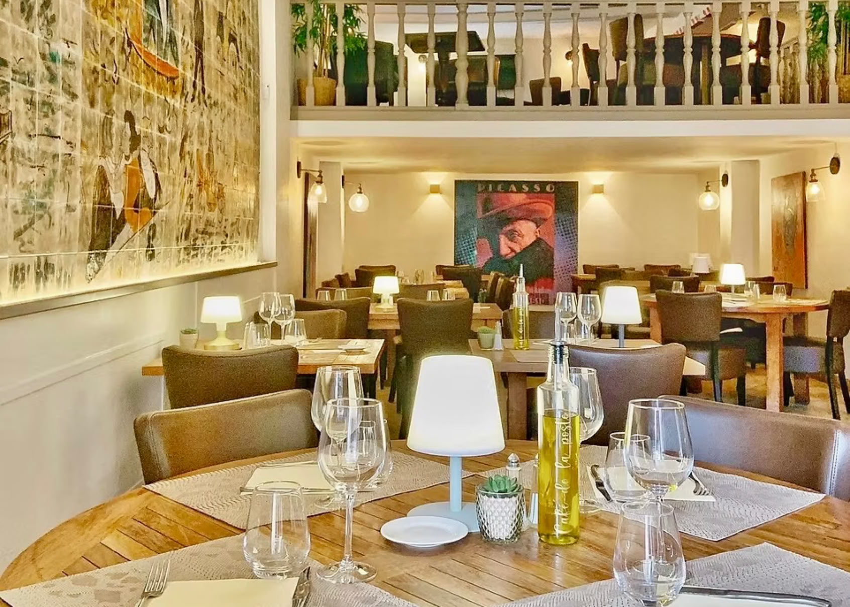 Le Café de la Poste, located in the heart of the village of Biot, has been a true local institution since 1885. With its period façade, shaded terrace under the plane trees by the fountain, and cozy interior featuring a mezzanine, faience mural, painted beams, and colorful chandelier, it offers a warm and authentic atmosphere. It’s a must-stop for anyone looking for a typical Provençal bistro, with a charming setting and quality Mediterranean cuisine at truly reasonable prices.