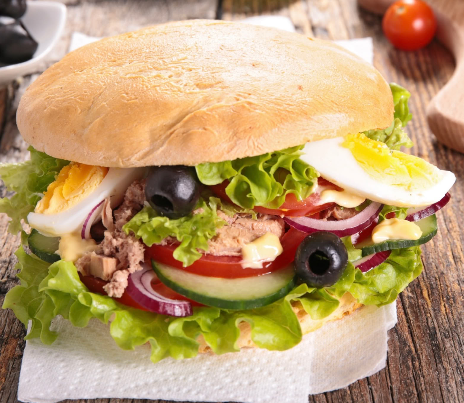 It’s an icon of Niçoise cuisine, simply the essence of the Niçoise salad... in a bread! A true street food, practical, complete, fresh, and deeply Mediterranean. "Pan bagnat" comes from the Niçard phrase "pan banhat," which means "wet bread." Originally, it was stale bread that was "wetted" with olive oil to make it tasty again. It’s a round bread (like country bread or pain bagnat bread) cut in half, filled with the ingredients of Niçoise salad, and especially without mayonnaise to stay true to tradition.