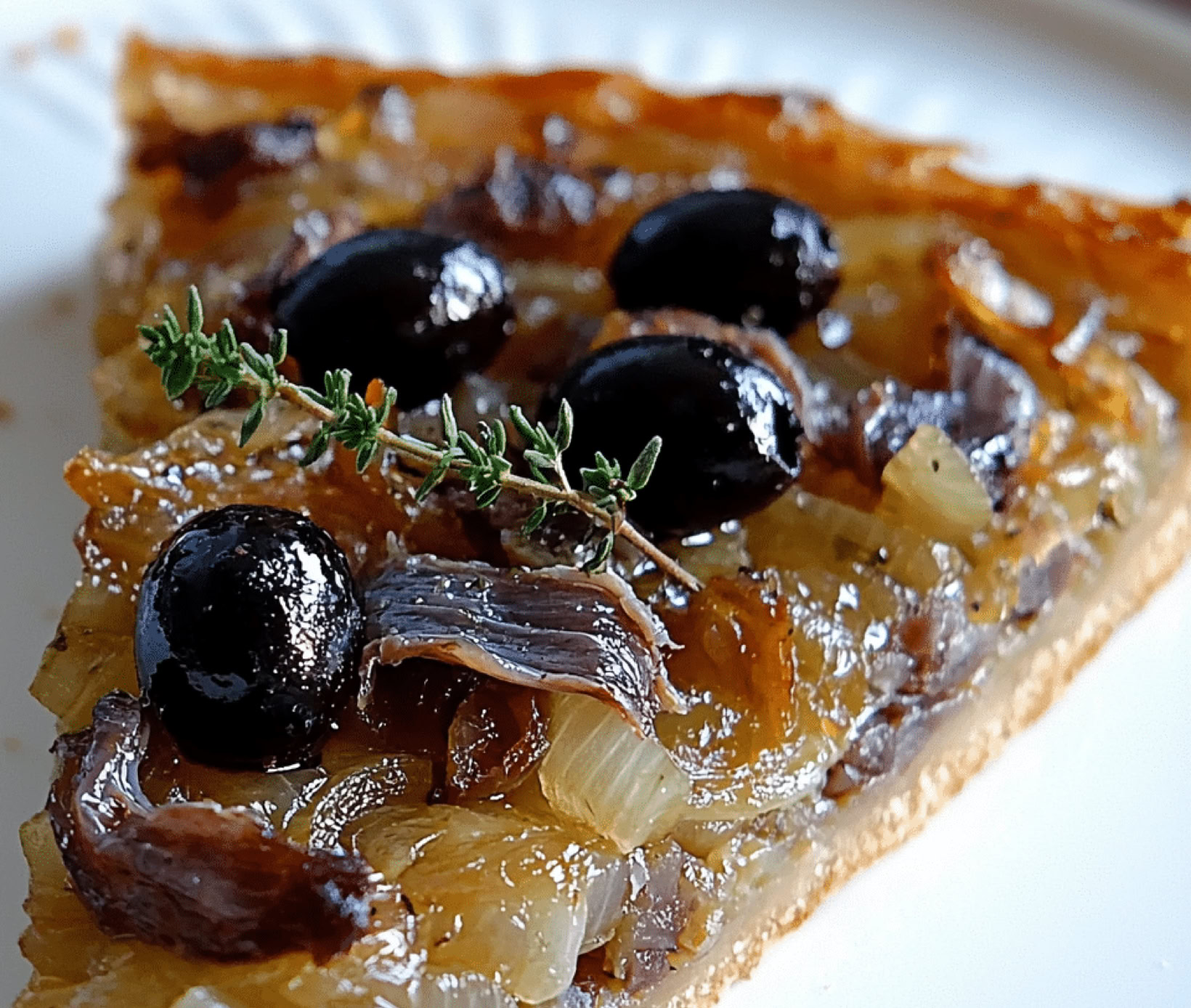 Une autre spécialité emblématique de la région niçoise, mais aussi de toute la Provence. C’est une sorte de tarte salée, qui ressemble un peu à une pizza, mais avec ses propres particularités. C’est une tarte à base de pâte à pain ou pâte à pizza, recouverte généreusement d’une compotée d’oignons doux, caramélisés lentement, avec des anchois (souvent en filets) et des olives noires. Parfois, on ajoute aussi des câpres.