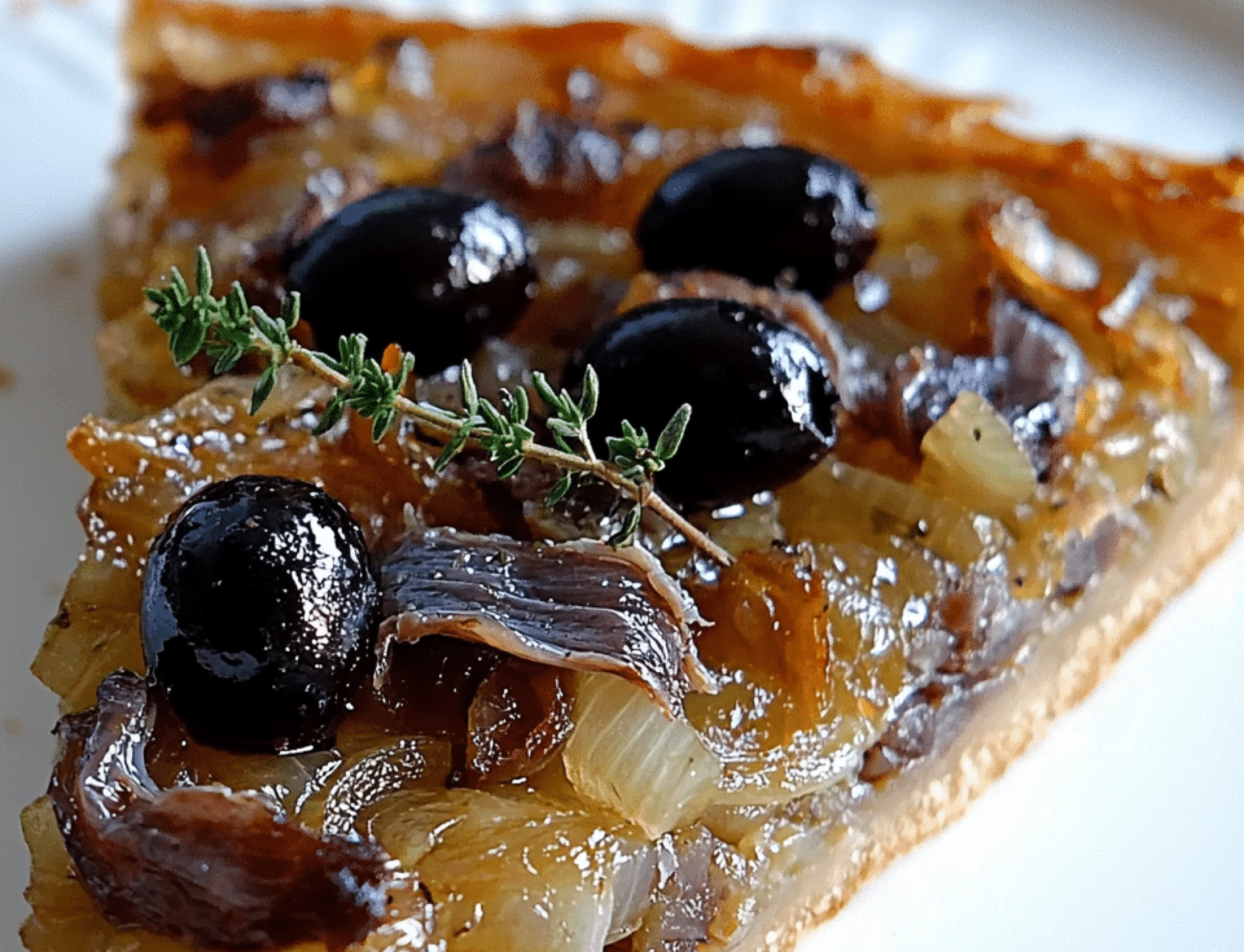 Another iconic specialty from the Nice region, and also widely enjoyed throughout Provence. It’s a kind of savory tart, somewhat similar to pizza, but with its own distinct character. It’s made with a bread dough or pizza dough base, generously topped with a sweet onion compote—slowly caramelized—along with anchovy fillets and black olives.