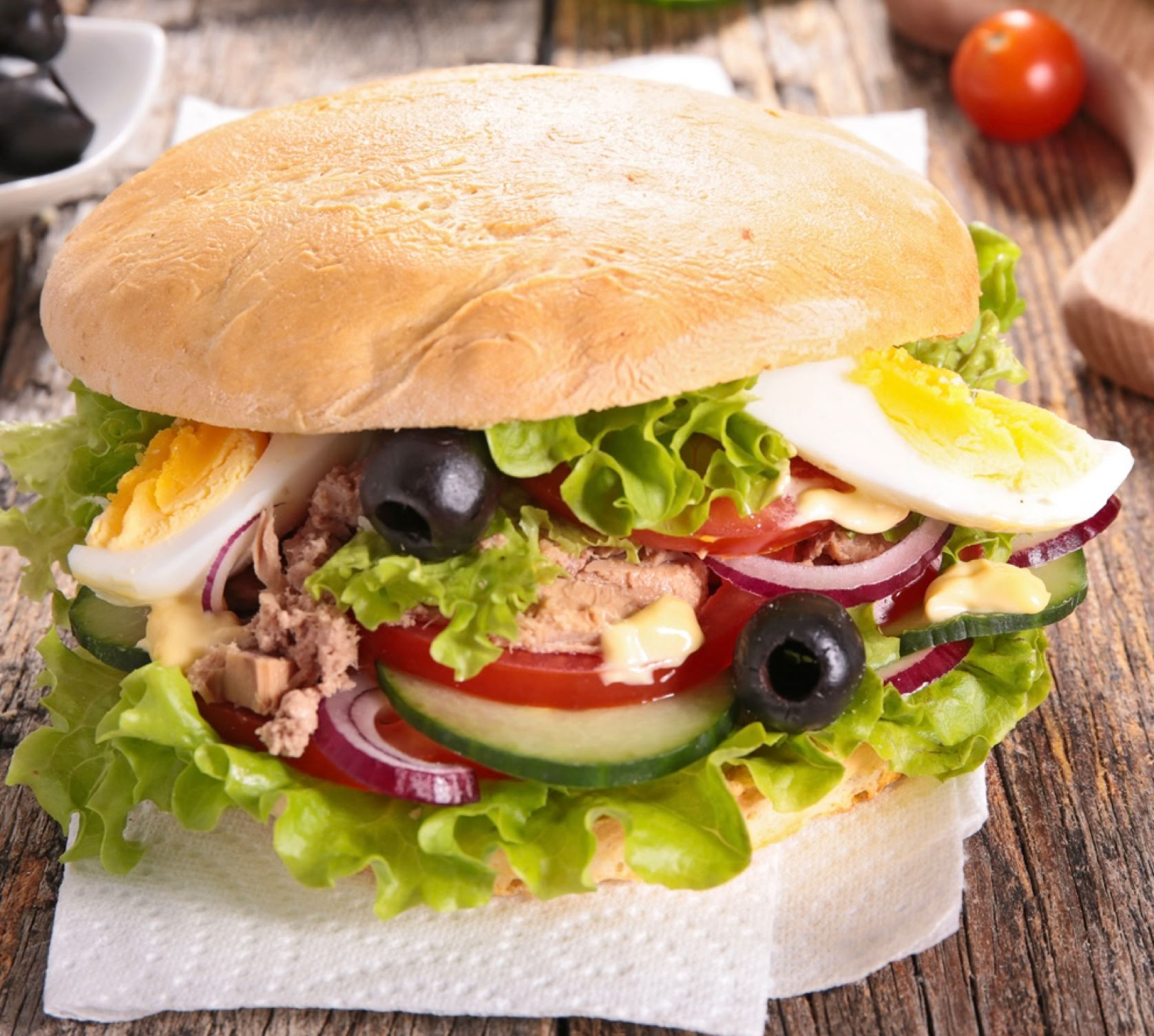 C’est une icône de la cuisine niçoise, tout simplement l’essence de la salade niçoise... dans un pain ! Un vrai plat de rue, pratique, complet, frais, et profondément méditerranéen. "Pan bagnat" vient du niçois "pan banhat", qui signifie "pain mouillé". Il s’agissait à l’origine de pain rassis qu’on "mouillait" avec de l’huile d’olive pour le rendre savoureux à nouveau.