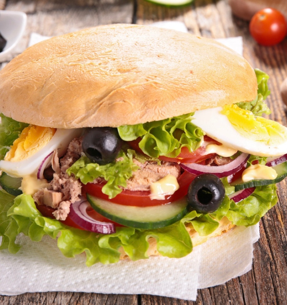 C’est une icône de la cuisine niçoise, tout simplement l’essence de la salade niçoise... dans un pain ! Un vrai plat de rue, pratique, complet, frais, et profondément méditerranéen. "Pan bagnat" vient du niçois "pan banhat", qui signifie "pain mouillé". Il s’agissait à l’origine de pain rassis qu’on "mouillait" avec de l’huile d’olive pour le rendre savoureux à nouveau.